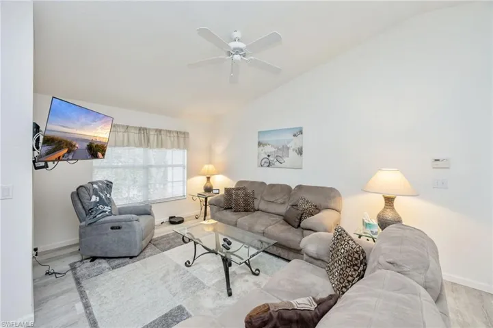 Living room featuring wood laminate finished floors, vaulted ceiling, and ceiling fan