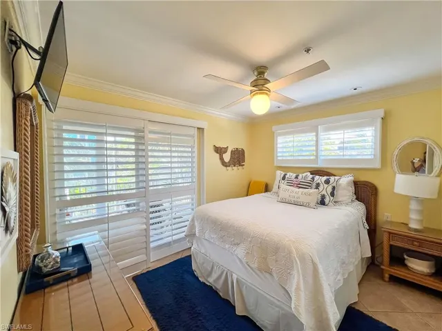 Bedroom featuring tile flooring, ceiling fan, multiple windows, and crown molding