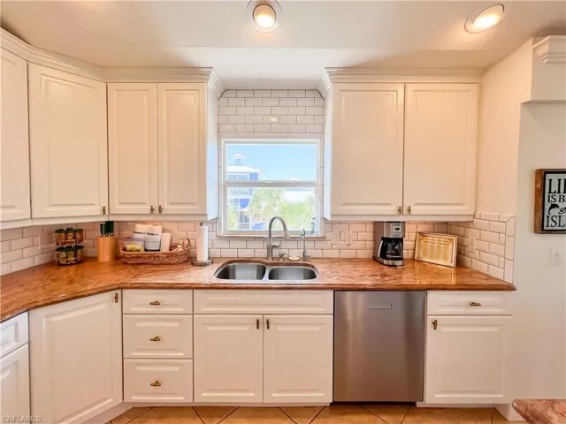 Kitchen featuring dishwasher, light tile floors, sink, and backsplash