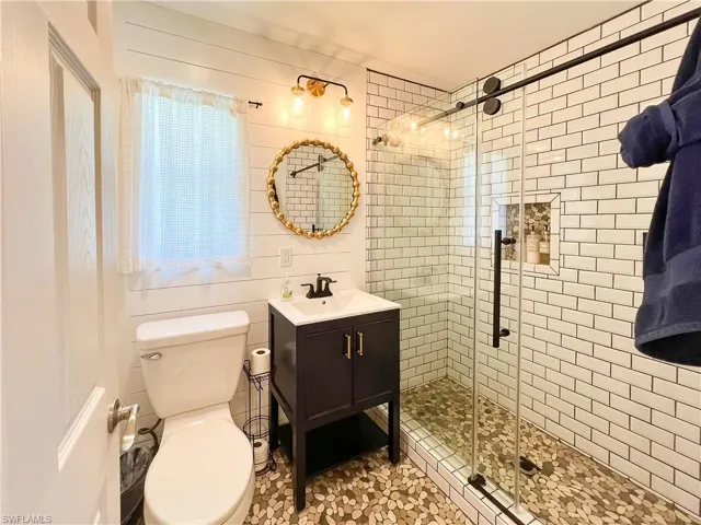 Bathroom featuring an enclosed shower, vanity, and toilet