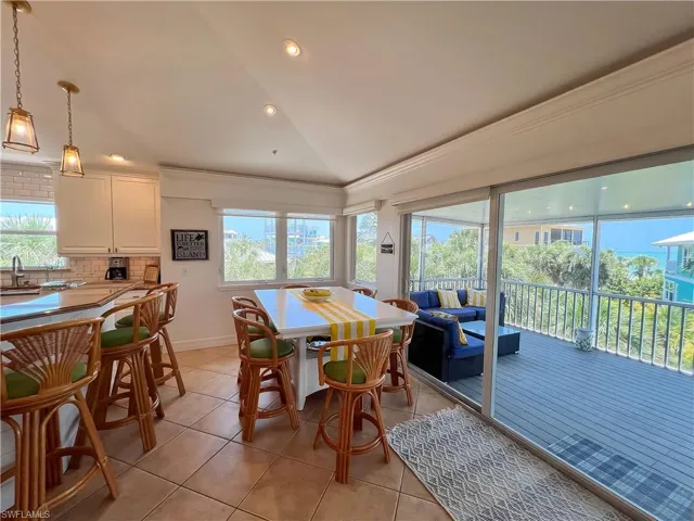 Dining space with light tile floors, a healthy amount of sunlight, and vaulted ceiling