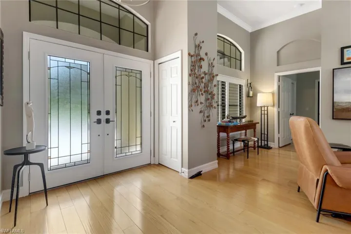 Foyer with french doors, light wood-type flooring, and a towering ceiling