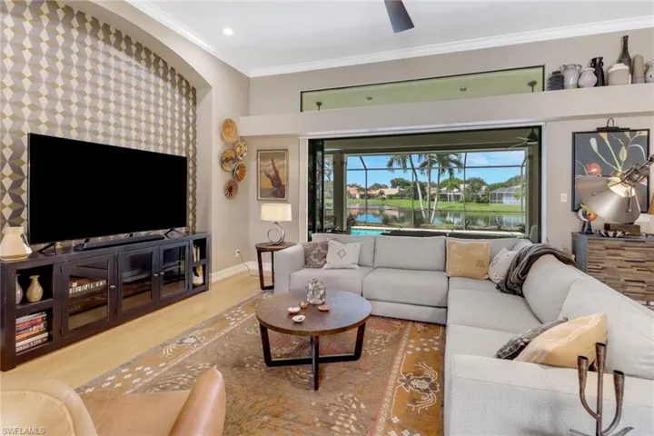 Living room with ornamental molding, a water view, ceiling fan, and hardwood / wood-style flooring