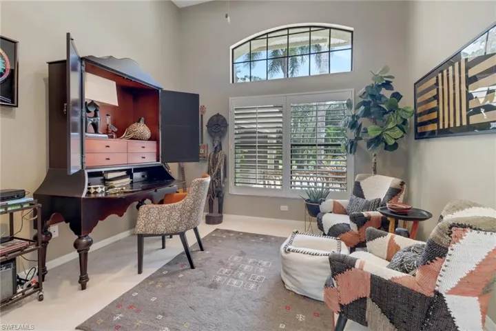 Carpeted home office with plenty of natural light and a high ceiling