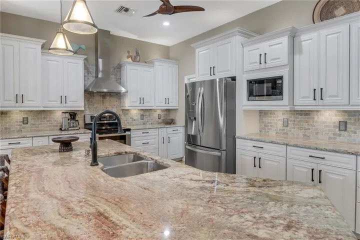 Kitchen featuring appliances with stainless steel finishes, wall chimney range hood, and white cabinets