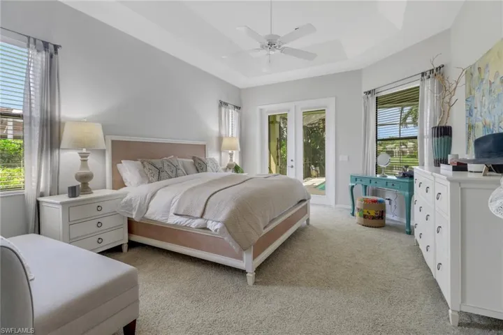 Carpeted bedroom featuring a raised ceiling, ceiling fan, french doors, and access to exterior