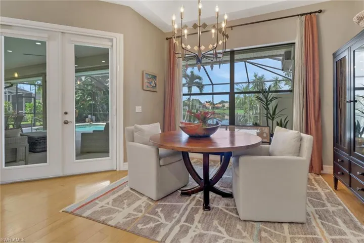 Dining space with a notable chandelier, light wood-type flooring, vaulted ceiling, and plenty of natural light