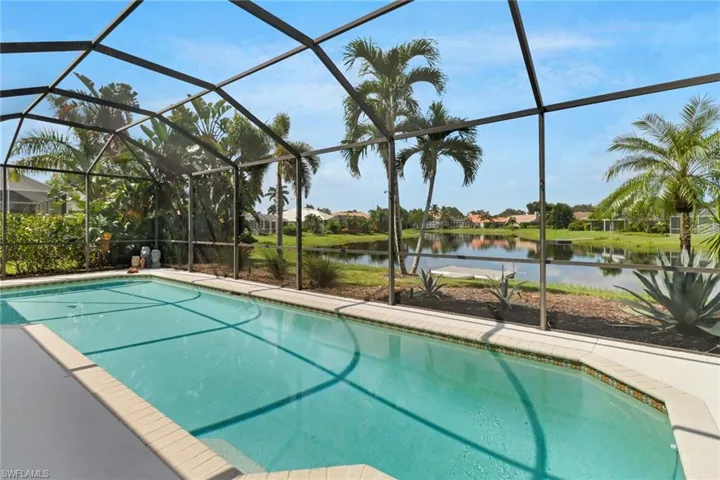 View of pool with a water view and glass enclosure