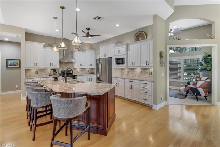 Kitchen with stainless steel appliances, white cabinetry, and a center island with sink