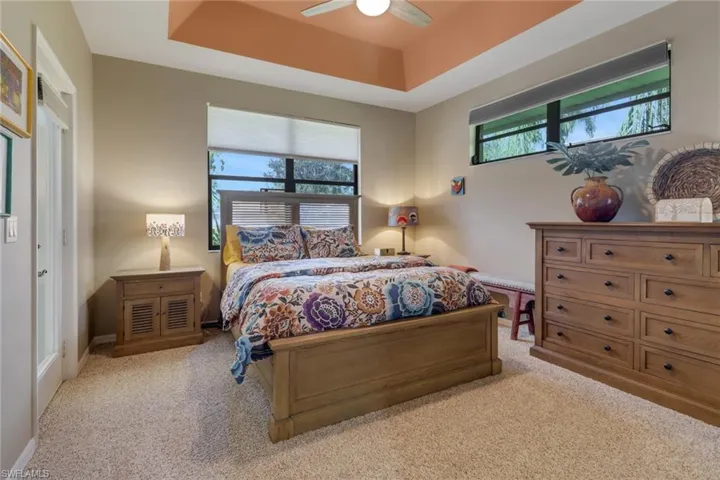 Carpeted bedroom featuring a tray ceiling and ceiling fan
