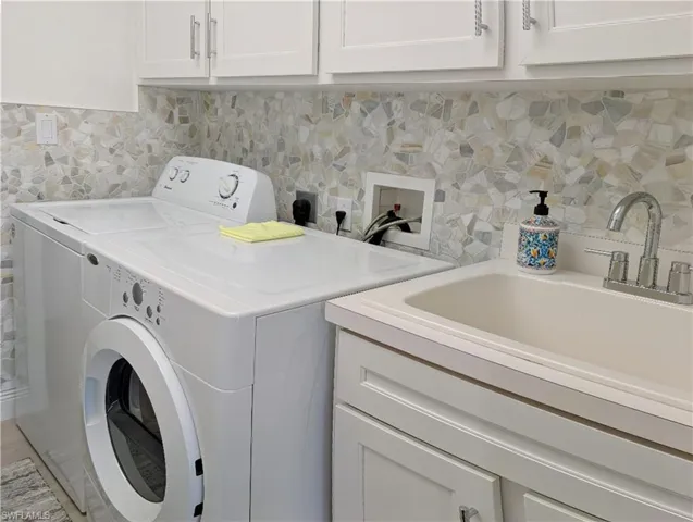 Laundry area featuring cabinets, washing machine and dryer, and sink