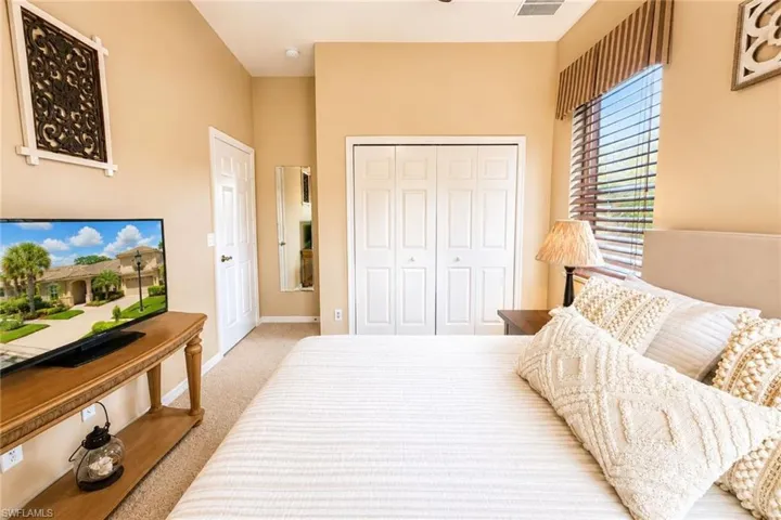 Bedroom featuring neutral wall paint, carpet flooring, a window with horizontal blinds, and a built-in closet with bi-fold doors