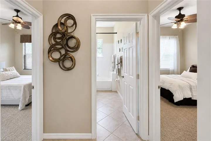 Interior hallway with light beige walls and white trim, featuring three doorways