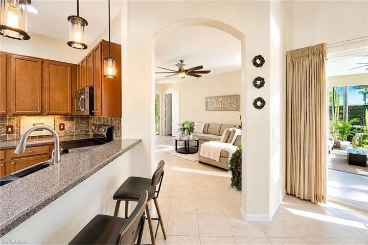 Kitchen featuring granite countertops, wood cabinetry, stainless steel appliances, and pendant lighting