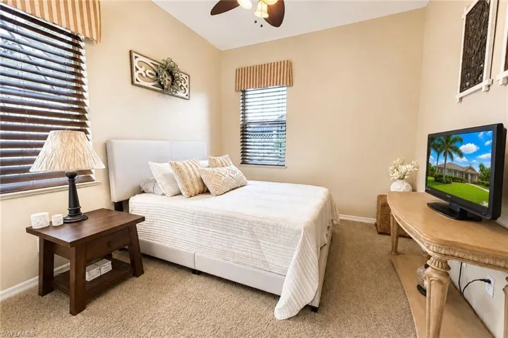 Carpeted room featuring two windows with horizontal blinds, a ceiling fan, and neutral-toned walls