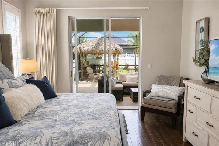 Indoor space featuring wood-finish flooring, plantation shutters, and sliding glass doors opening to an outdoor lanai