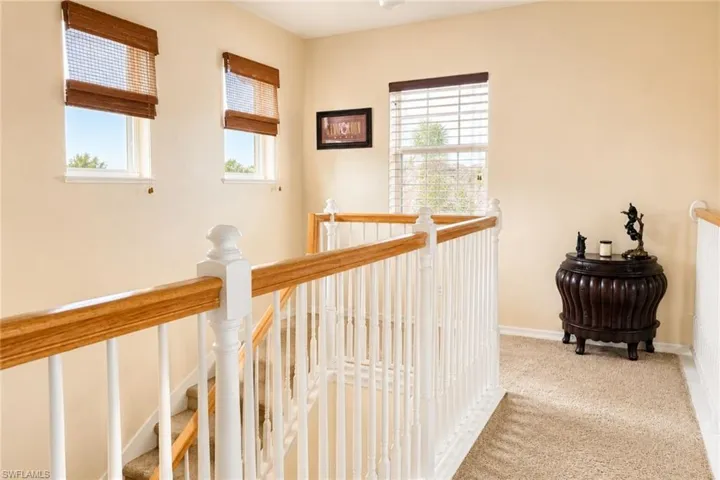 Upper landing with carpeted flooring, white painted balusters, and natural wood handrails