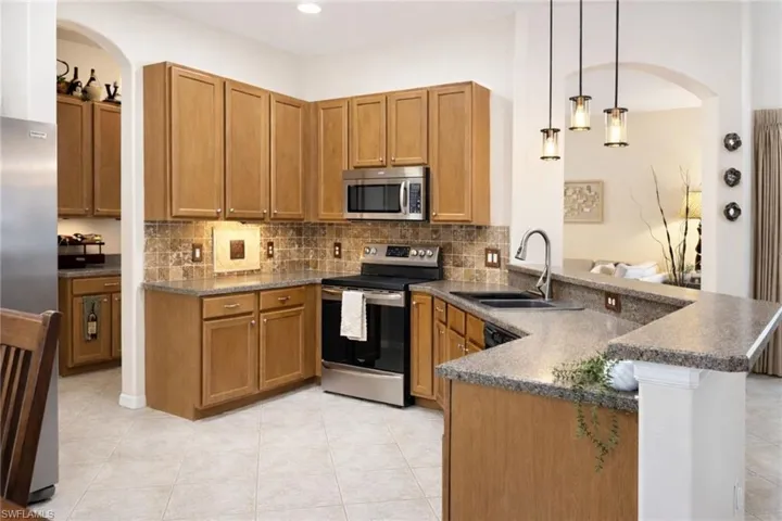 Well-appointed kitchen featuring light wood cabinetry, stainless steel appliances, and a tile backsplash