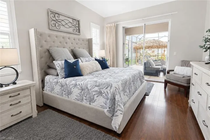 Bedroom featuring wood-finish flooring, sliding glass doors to the exterior, and plantation shutters