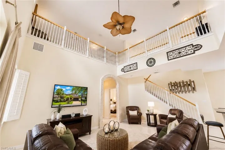 Spacious living area featuring a vaulted ceiling and a second-story balcony with white balusters