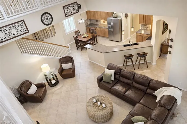 Open-concept living space featuring a two-story ceiling, tile flooring, and a kitchen with wood cabinetry