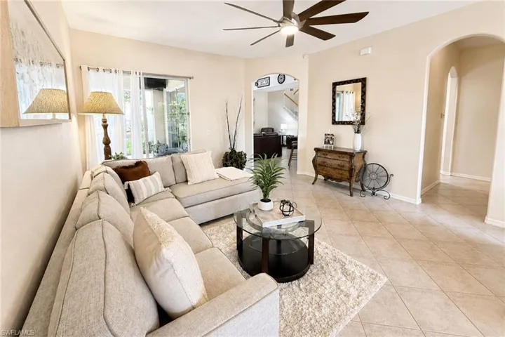 Spacious living area featuring large format tile flooring, a dark-toned ceiling fan, and sliding glass doors to the exterior