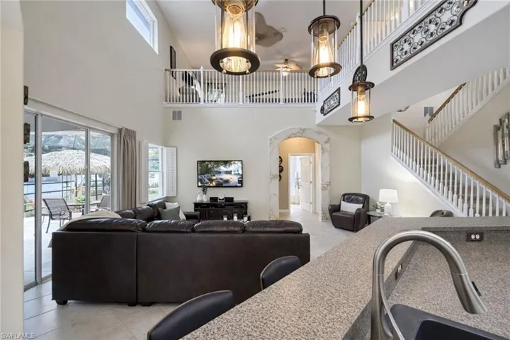 Two-story living area featuring a prominent staircase with wood handrails, a second-story balcony overlooking the space, and a high ceiling with clerestory windows