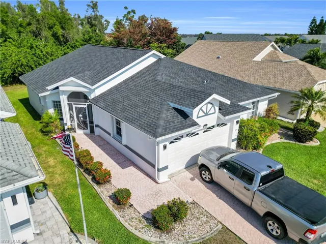 Modern single-story residence featuring a dark gray asphalt shingle roof, a two-car garage with white paneled doors, and a decorative gable dormer