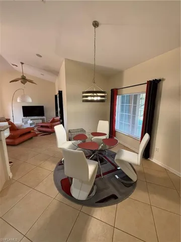 Dining space featuring light tile patterned floors, high vaulted ceiling, and ceiling fan