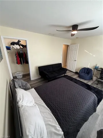 Bedroom with wood finished floors, a spacious closet, and a ceiling fan