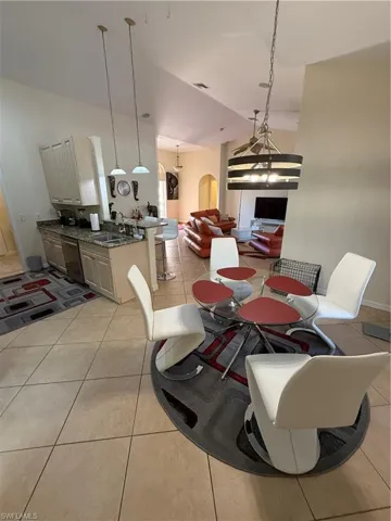 Dining room featuring arched walkways, light tile patterned flooring, and high vaulted ceiling