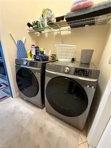 Washroom with washing machine and clothes dryer and light colored carpet