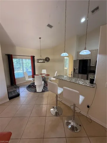 Kitchen featuring hanging light fixtures, dark stone countertops, fridge, a breakfast bar, and a peninsula