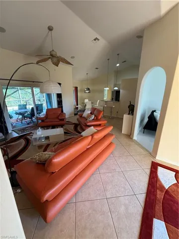 Living area featuring light tile patterned floors, high vaulted ceiling, and a ceiling fan