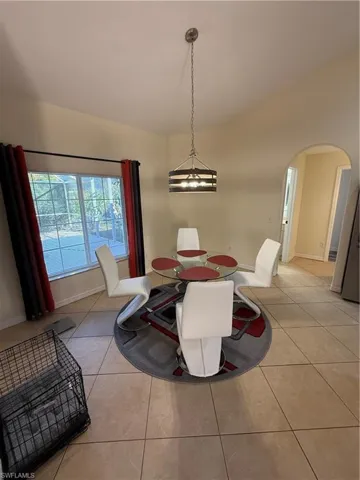 Dining area with light tile patterned flooring, arched walkways, and vaulted ceiling