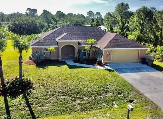 Single story home featuring stucco siding, driveway, a front yard, and roof with shingles