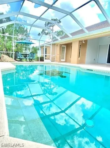 Outdoor pool featuring a sunroom, a lanai, and a patio area