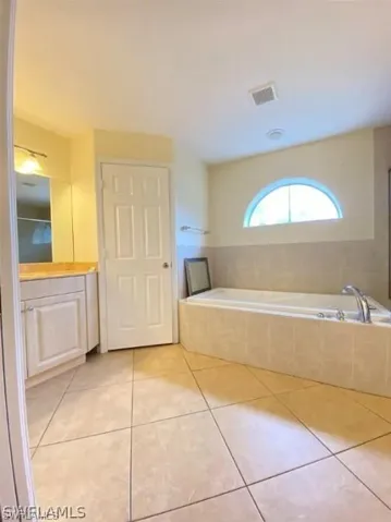 Bathroom featuring vanity, a bath, and light tile patterned floors