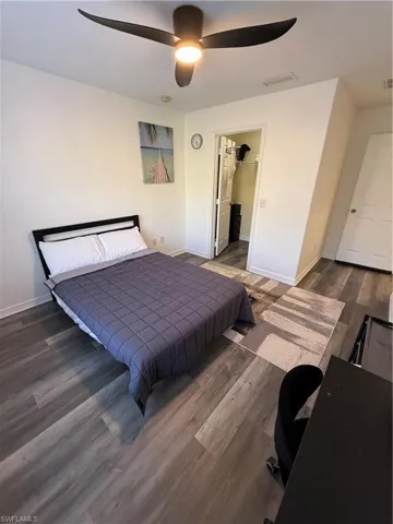 Bedroom featuring dark wood-style floors, a spacious closet, a desk, and ceiling fan