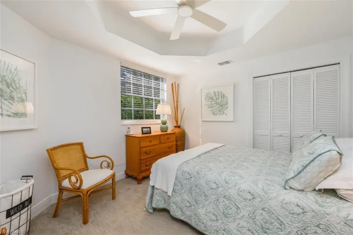 Bedroom with a tray ceiling, carpet floors, a ceiling fan, and a closet