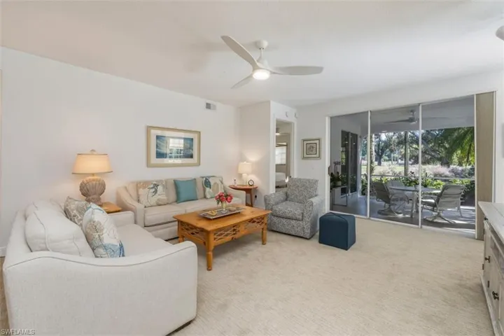 Living room with light carpet, a ceiling fan, and a sunroom