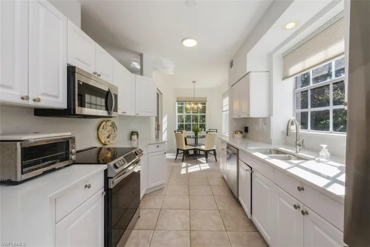 Kitchen featuring white cabinets, stainless steel appliances, light tile patterned floors, a chandelier, and recessed lighting