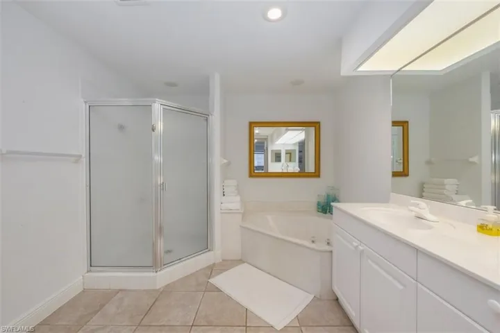 Bathroom featuring a bath, light tile patterned flooring, a stall shower, vanity, and recessed lighting
