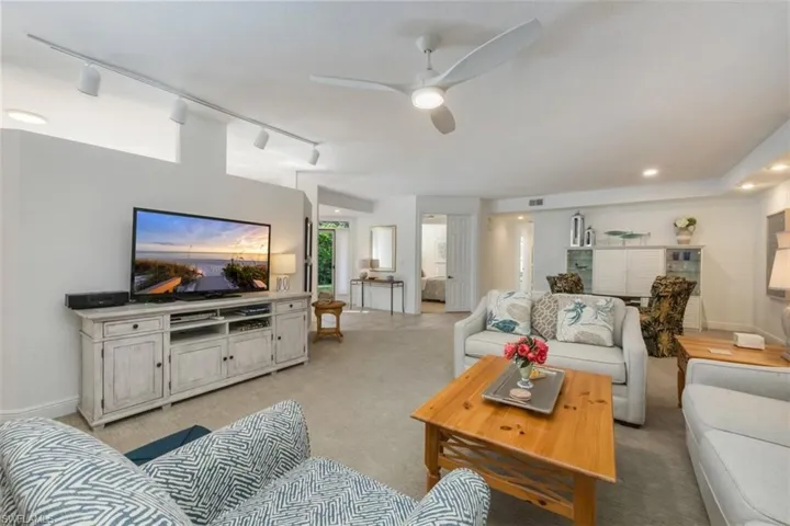 Living area with light carpet, rail lighting, and ceiling fan