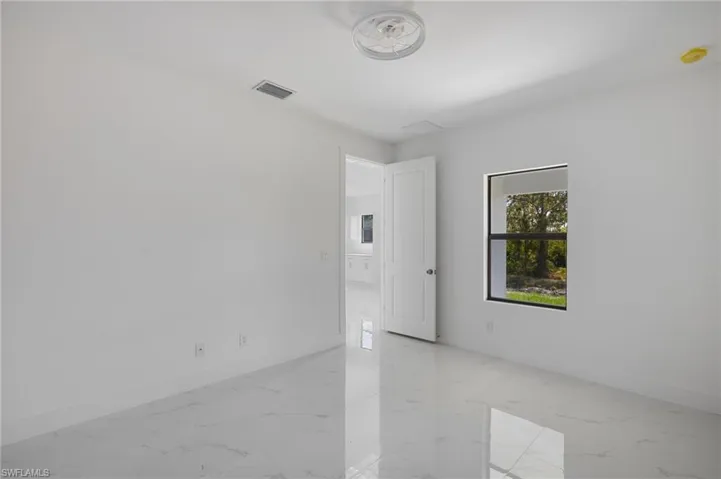 Unfurnished room featuring light marble finish flooring, baseboards, and a smoke detector