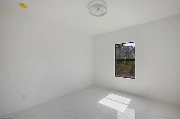 Unfurnished room featuring light marble finish floors and baseboards