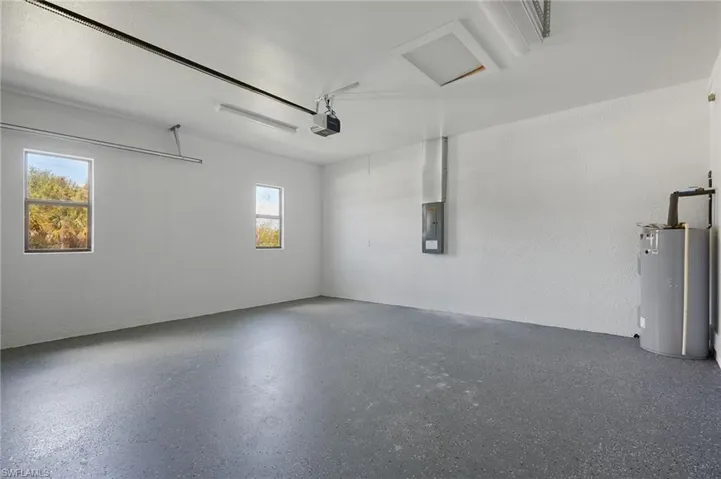 Garage with gas water heater, a garage door opener, and electric panel
