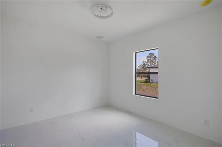 Spare room with baseboards, marble finish floors, and a smoke detector