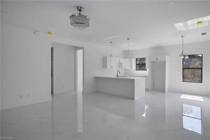 Kitchen with a peninsula, white cabinets, light marble finish flooring, and a chandelier