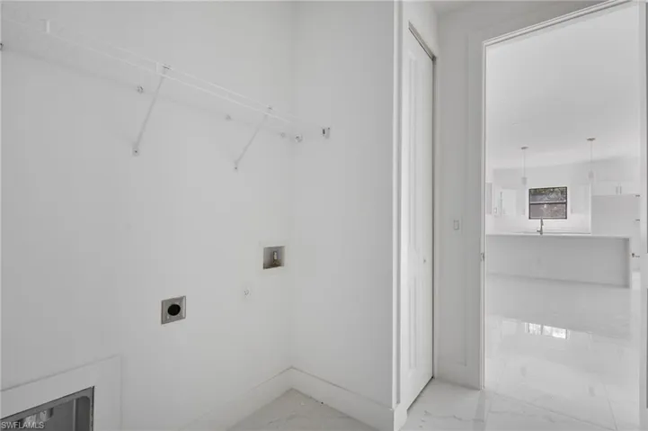Laundry area featuring hookup for a washing machine, electric dryer hookup, light marble finish floors, and baseboards